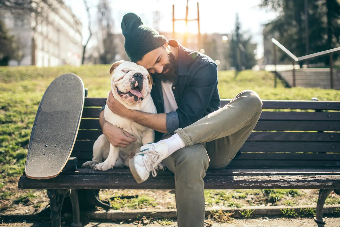 Ein Mann umarmt seinen Hund auf einer Bank