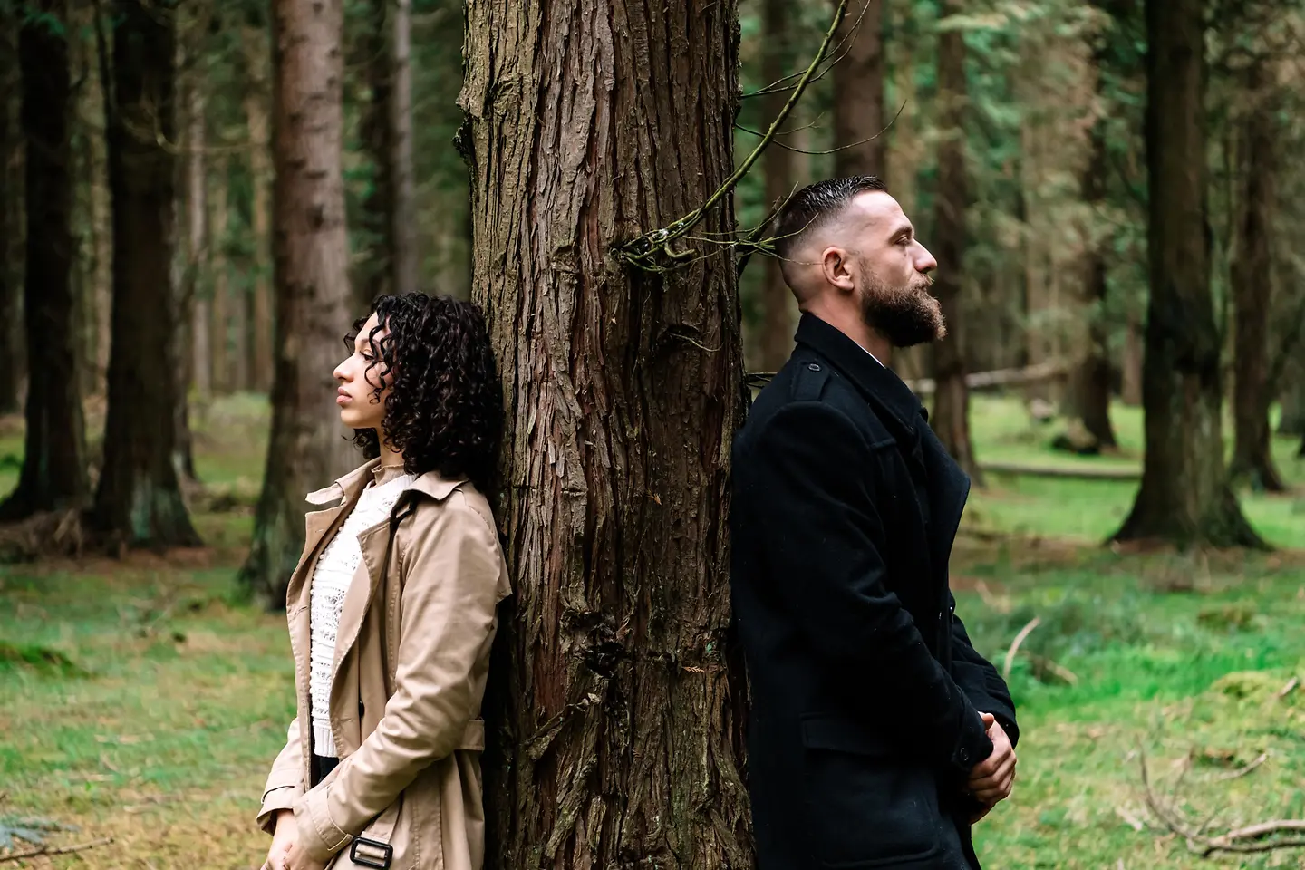 Paar steht im Wald an einen Baum gelehnt. 