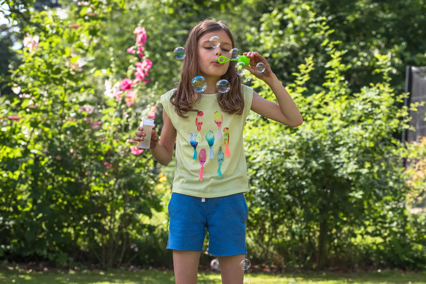 Ein einsames Mädchen pustet im Garten Seifenblasen. 