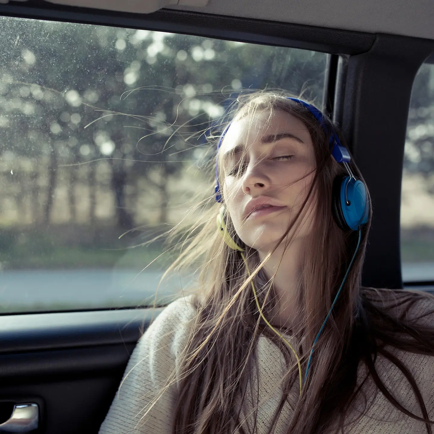 Eine junge Frau sitzt in einem Auto und trägt Kopfhörer
