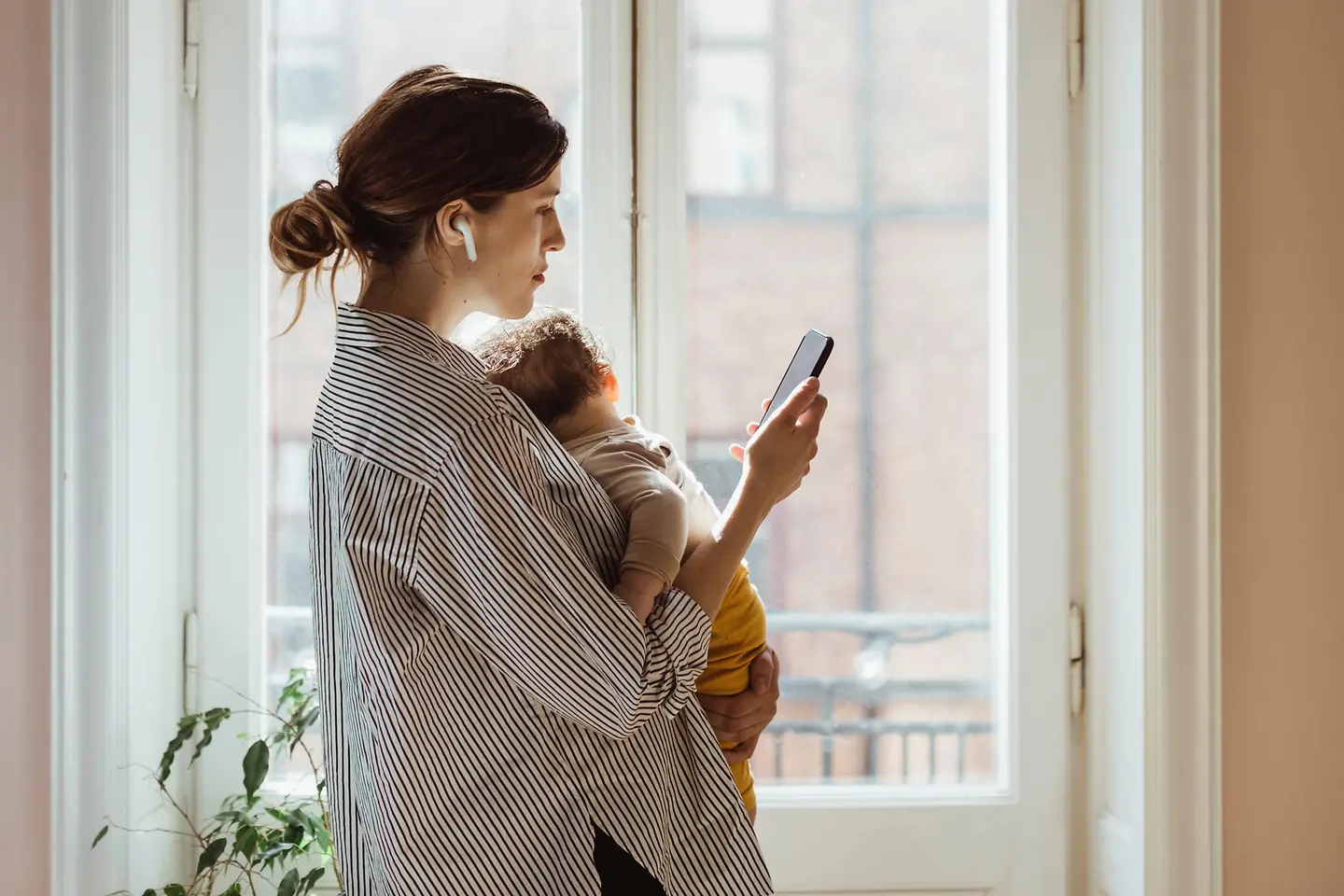 Mutter mit Kind auf dem Arm ruft Arzt an