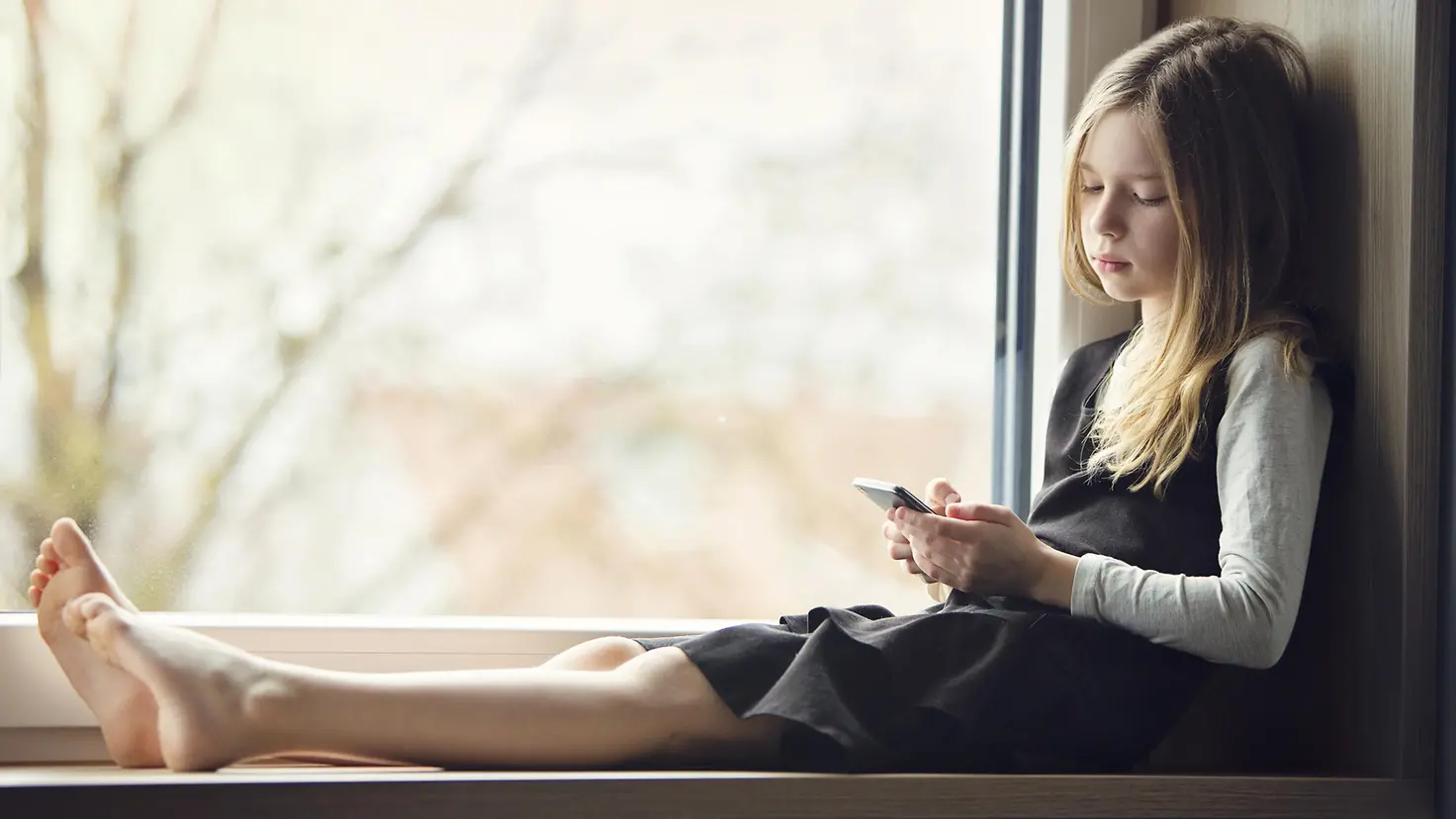 kleines Mädchen schaut enttäuscht auf ihr Handy