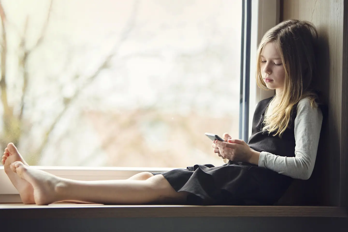 kleines Mädchen schaut enttäuscht auf ihr Handy