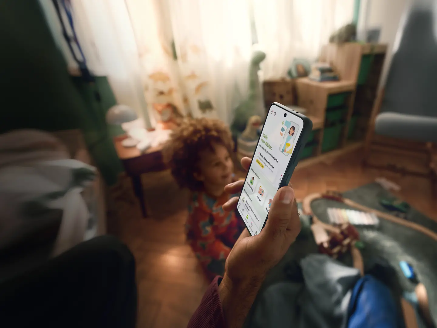 Ein Familienvater hält sein Handy in der Hand, auf dem der Startbildschirm der Teledoktor-App zu sehen ist. 