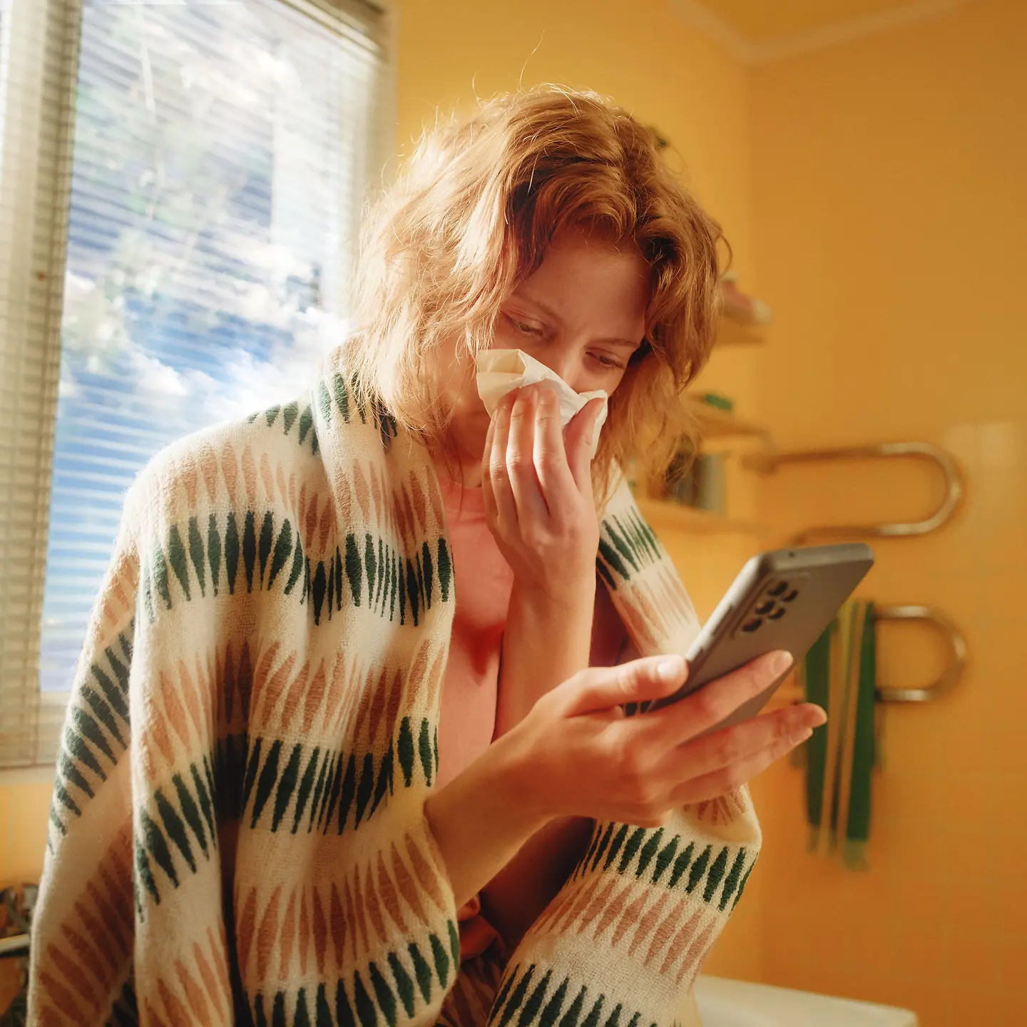 Eine erkältete Frau nutzt die Teledoktor App