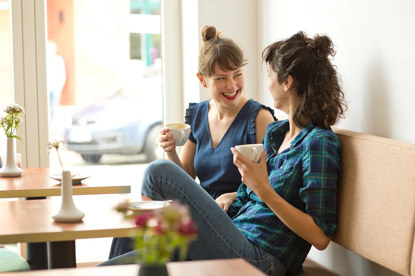 Zwei junge Frauen sitzen ganz entspannt bei einem Kaffee und unterhalten sich