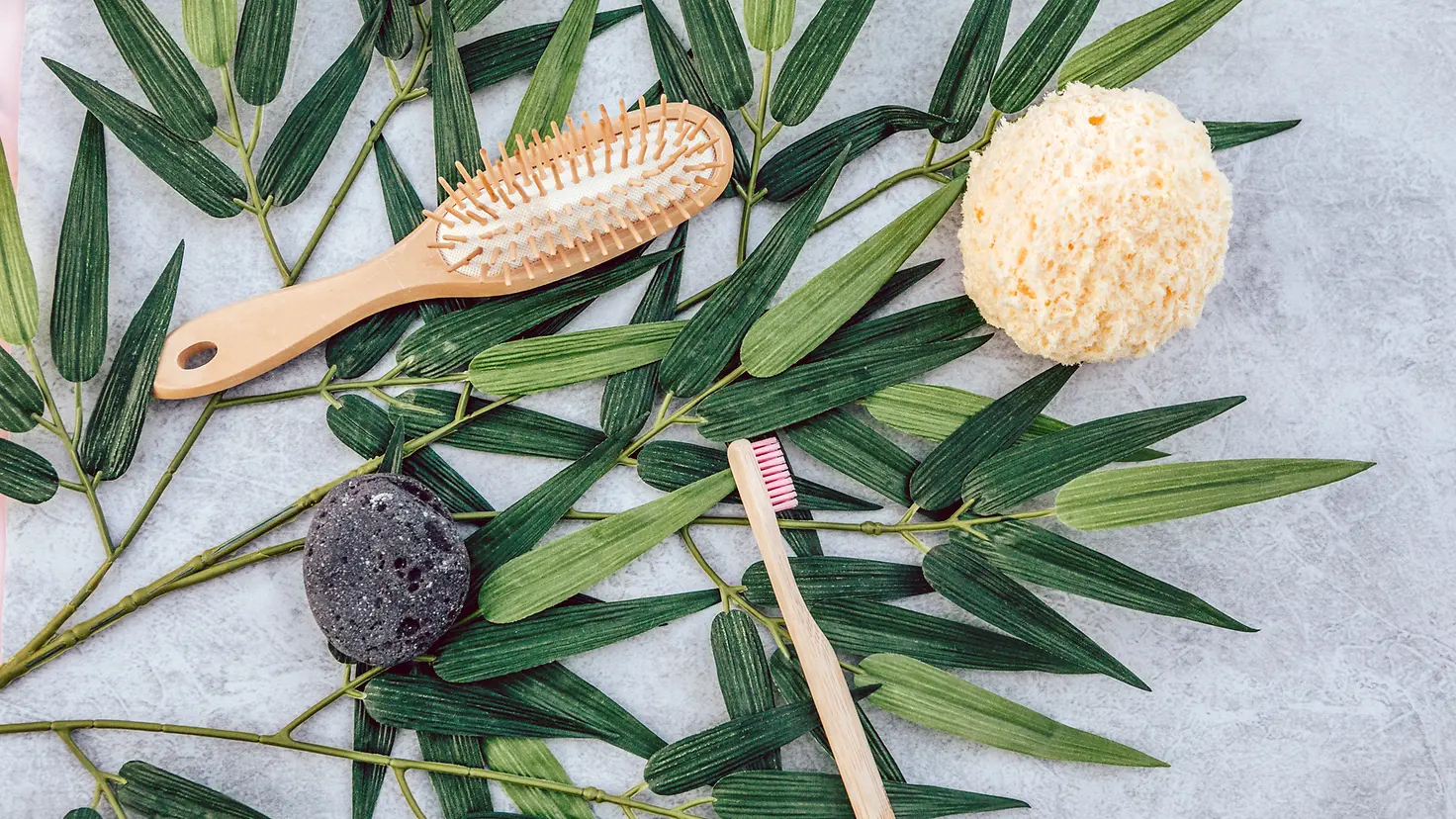 Flatlay mit einer Haarbürste, einer Zahnbürste, einem Schwamm und einem Seifenstück