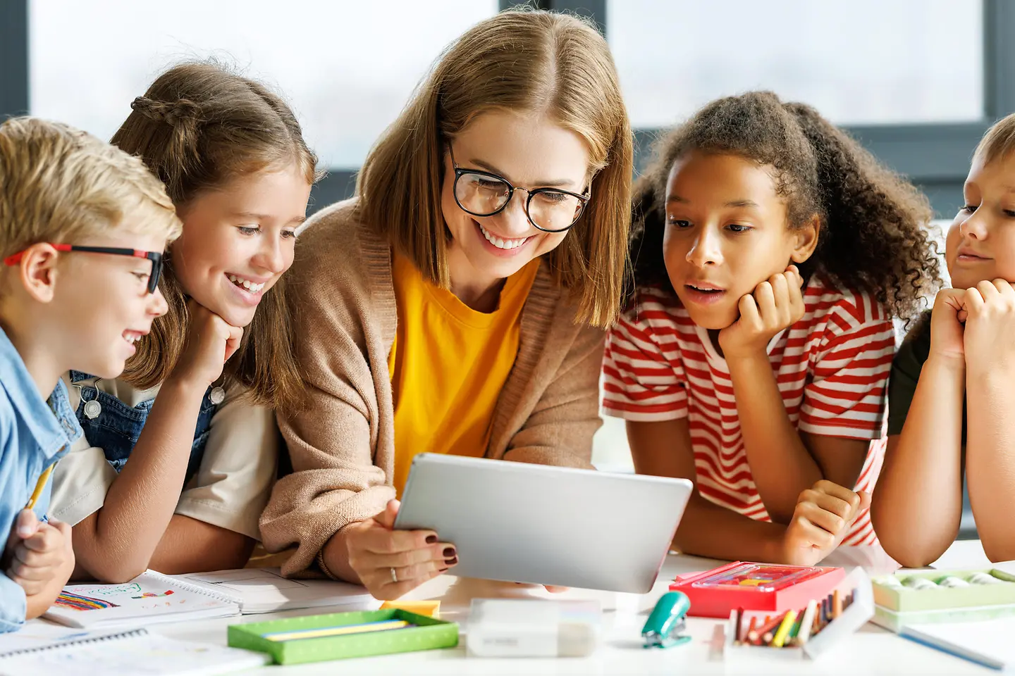 Zu sehen sind Kinder am Tisch mit einer Frau 