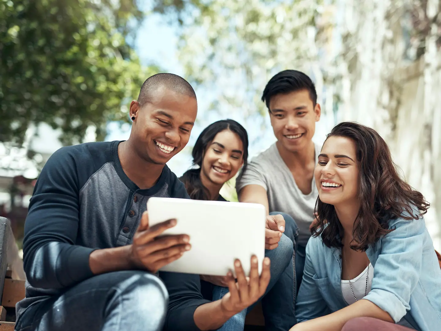 Vier junge Menschen schauen auf ein Tablet