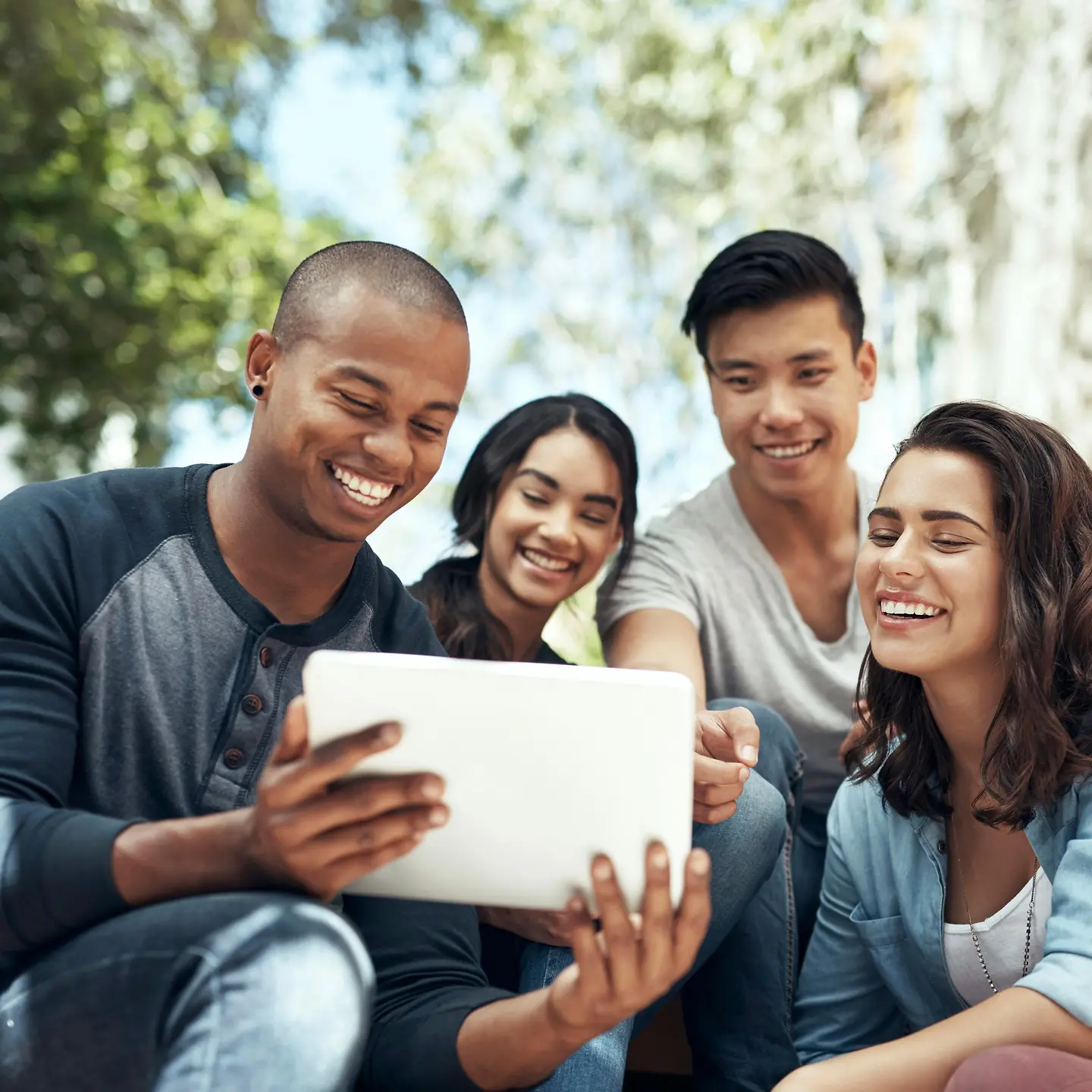 Vier junge Menschen schauen auf ein Tablet