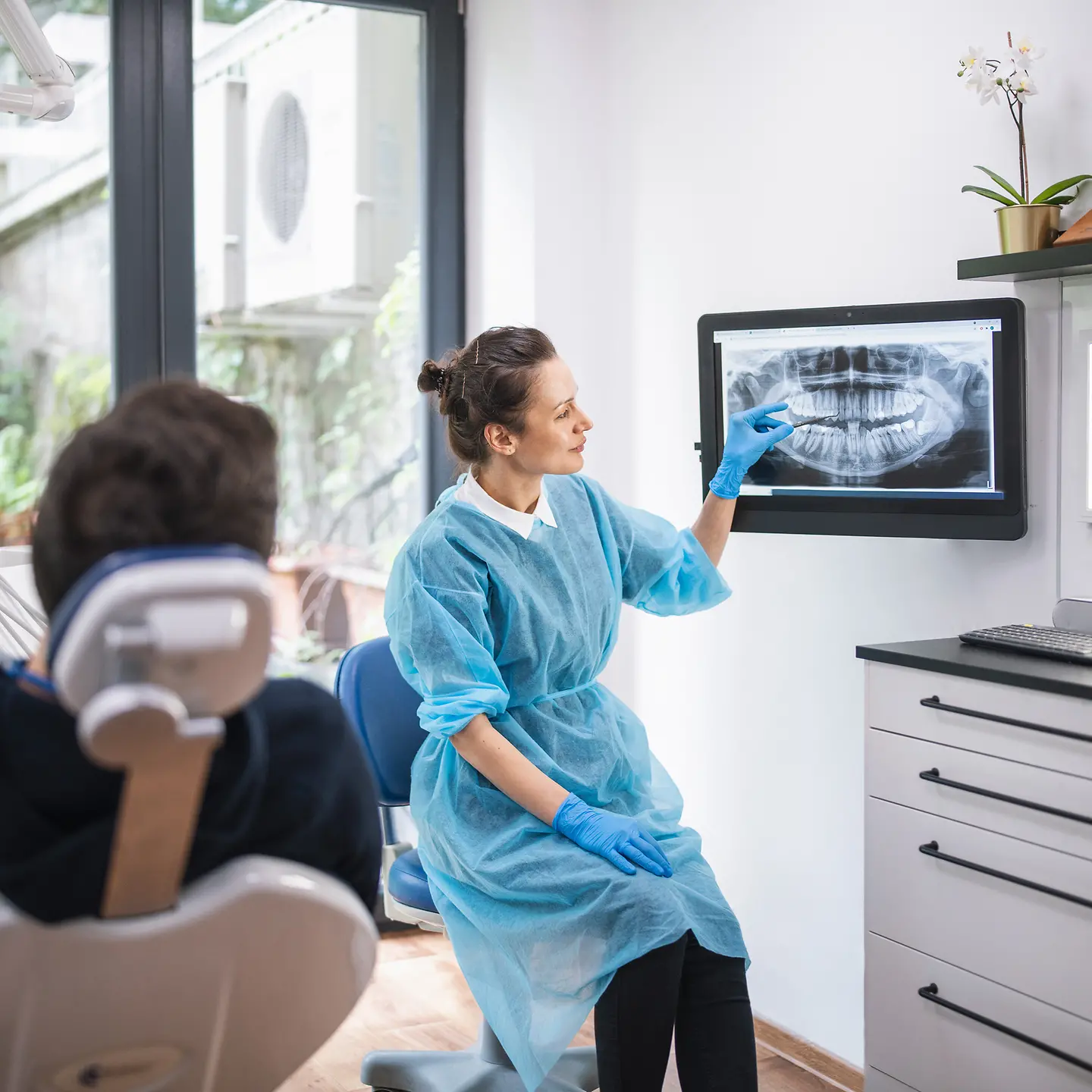 Eine Zahnärztin zeigt dem Patienten ein Röntgenbild von seinem Gebiss