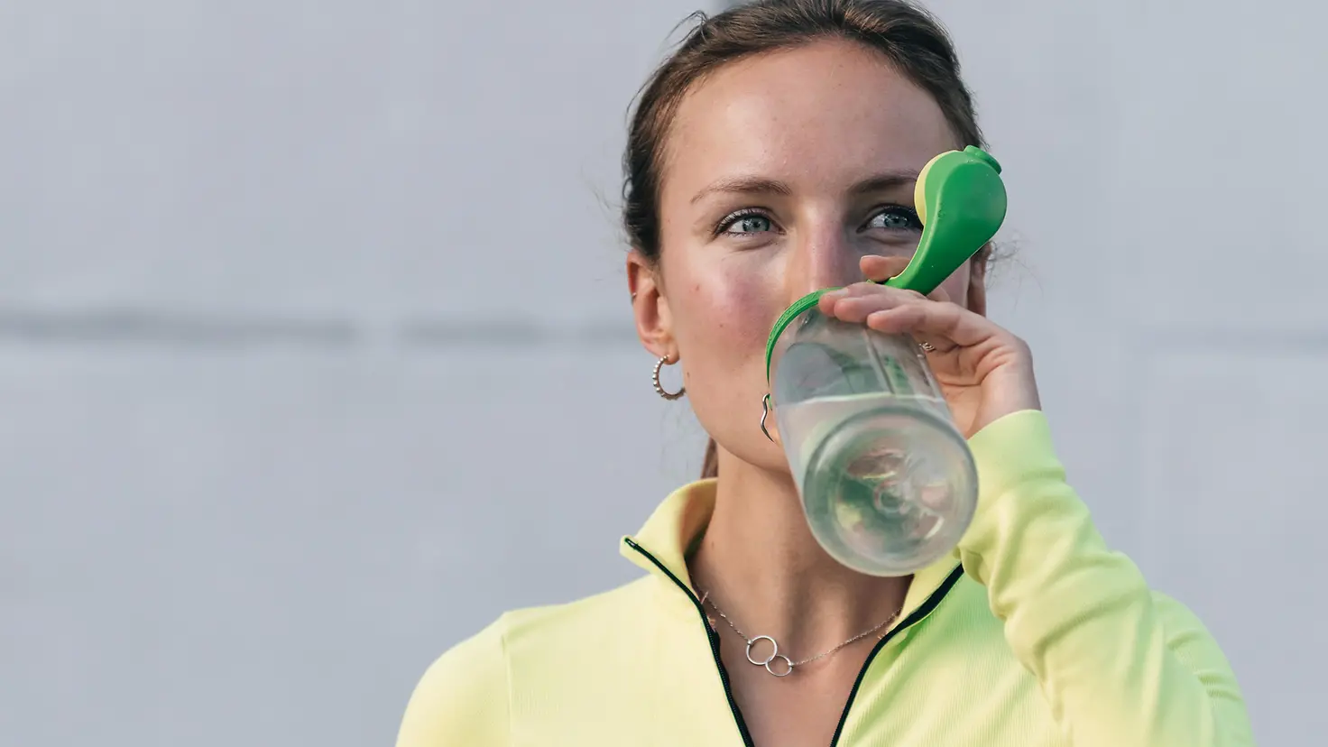 Frau trinkt nach dem Sport aus ihrer Wasserflasche