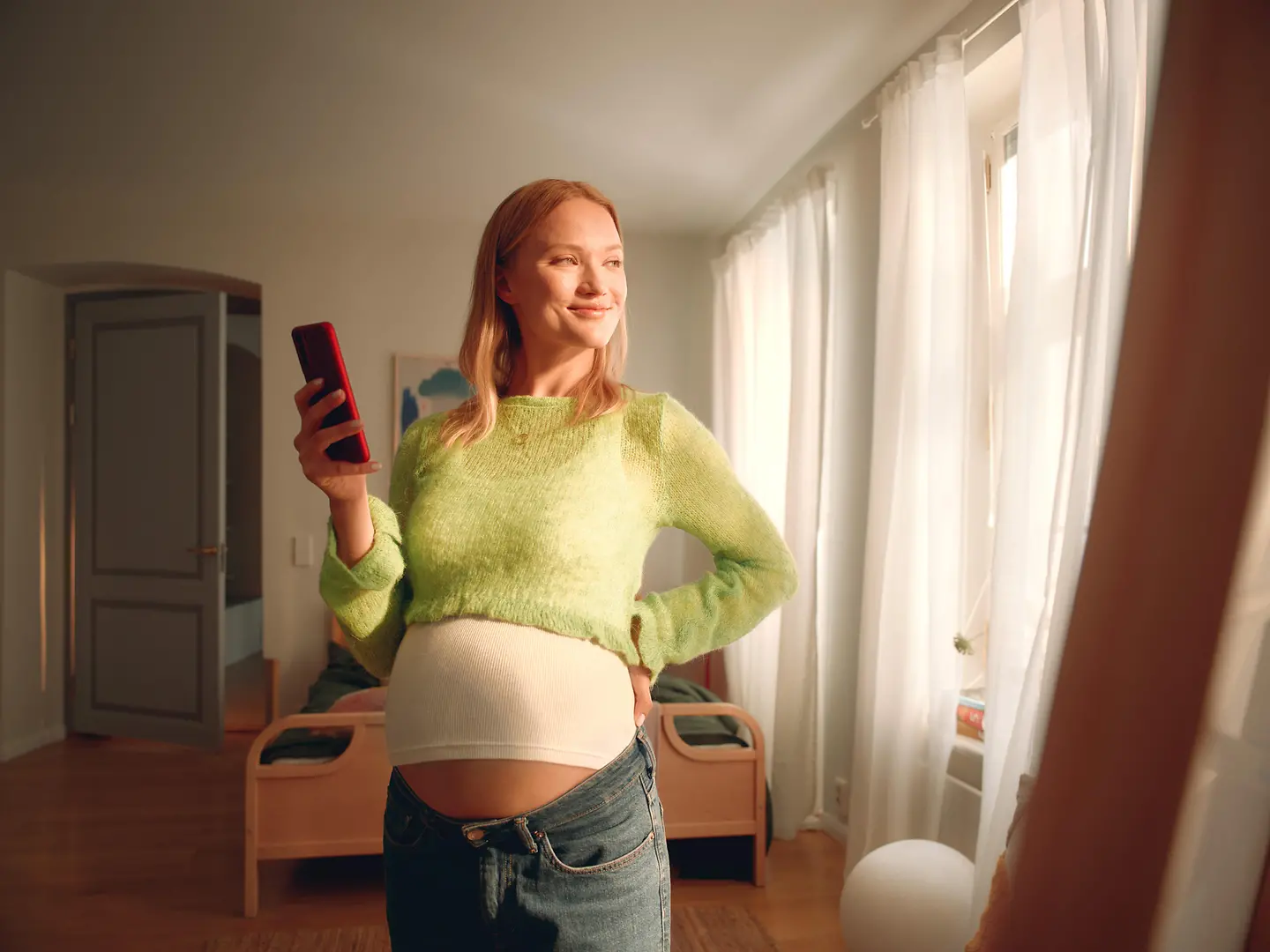 Eine schwangere Frau hält ein Handy in der Hand. 