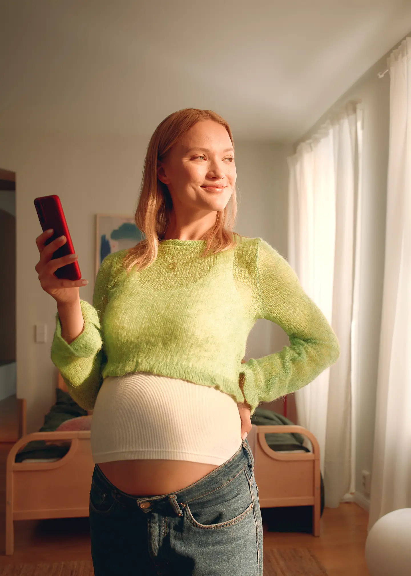 Eine schwangere Frau hält ein Handy in der Hand. 