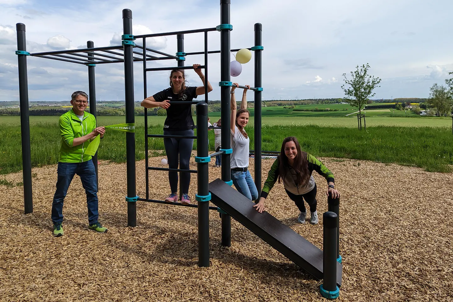 Vier Personen führen Übungen an einem Klettergerüst vor, das eine Station vom Fitness HotSpot ist.
