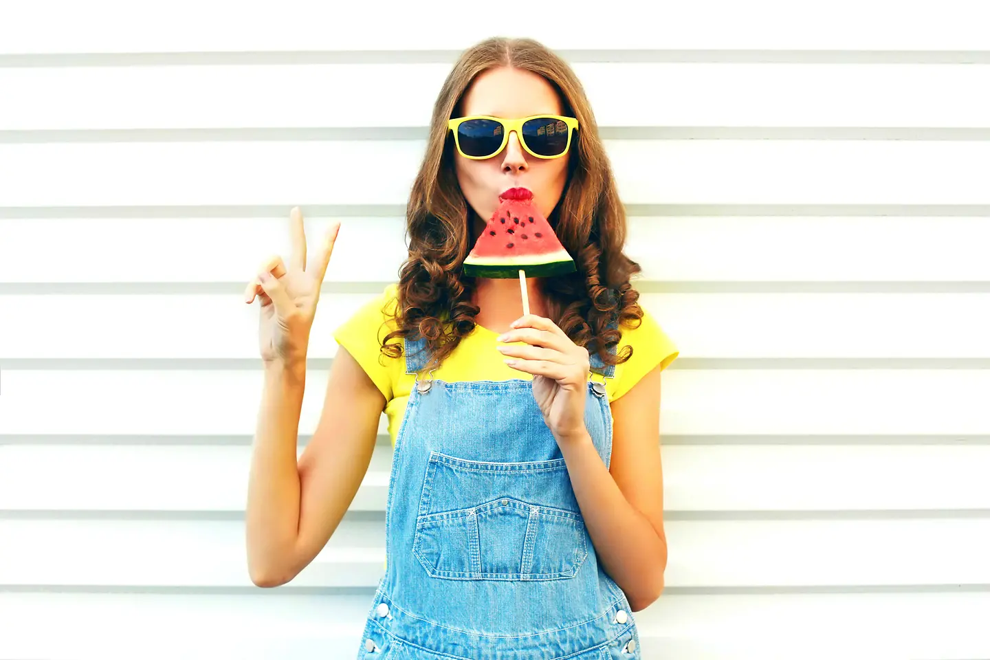 Zu sehen ist eine Frau mit einem Stück Melone am Stiel
