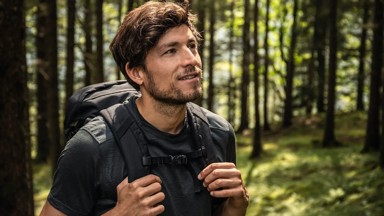 Ein Mann mit Rucksack macht einen Waldspaziergang. Bewegung tut bei psychischen Erkrankungen wie einer Schizophrenie gut.