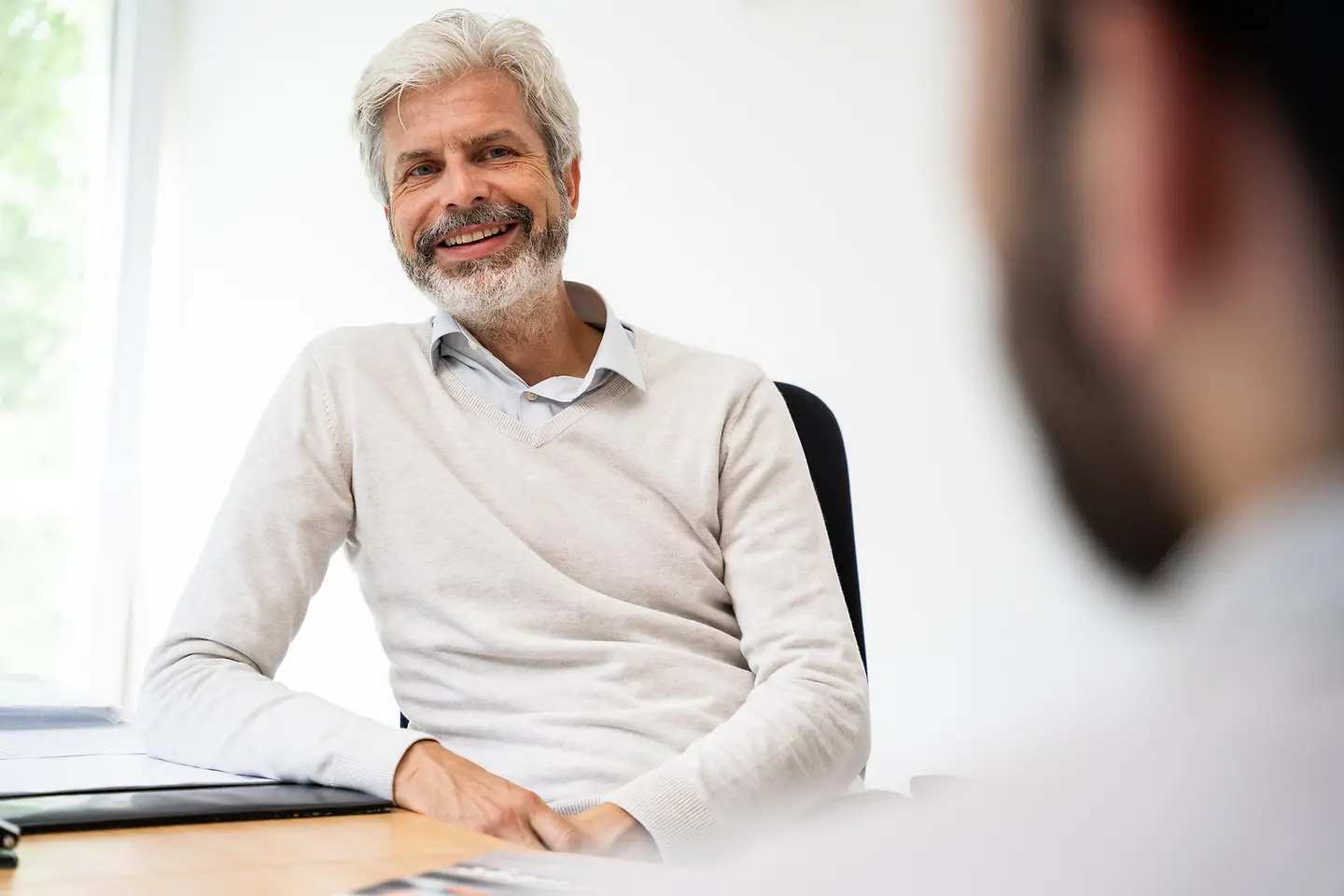 Gesundheitswissenschaftler Prof. Dr. Tobias Esch sitzt einem Gesprächspartner gegenüber