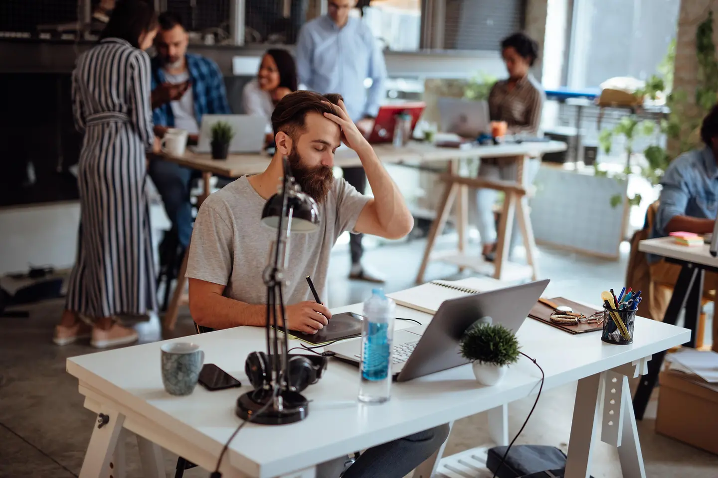 Mann sitzt im Büro mit Kopfschmerzen