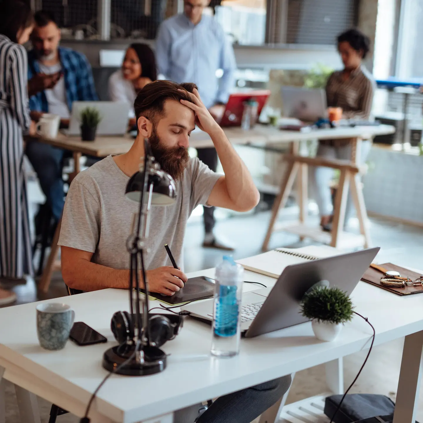 Mann sitzt im Büro mit Kopfschmerzen