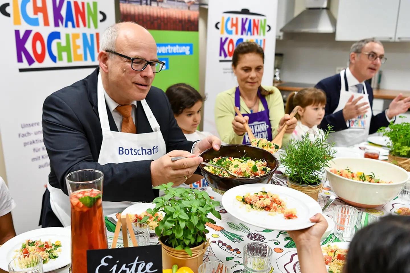 Ein Mann verteilt eine Speise aus einer Pfanne auf Teller
