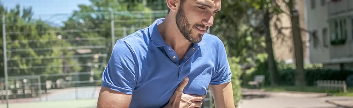 ein junger Mann greift sich mit der Hand an seine linke Brust