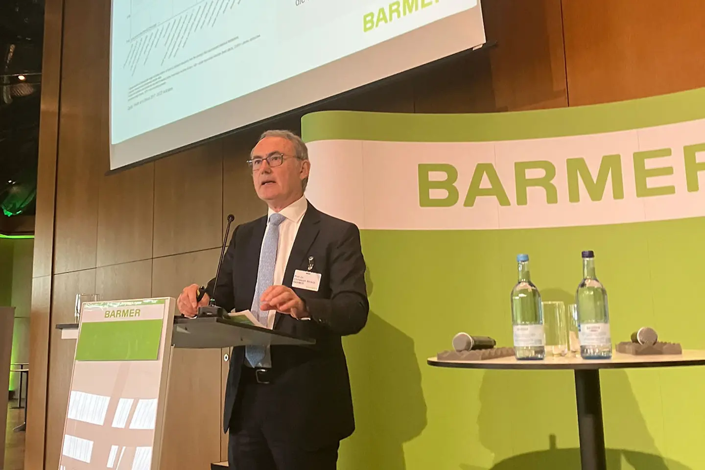 Ein Mann steht an einem Rednerpult und hält einen Vortrag.