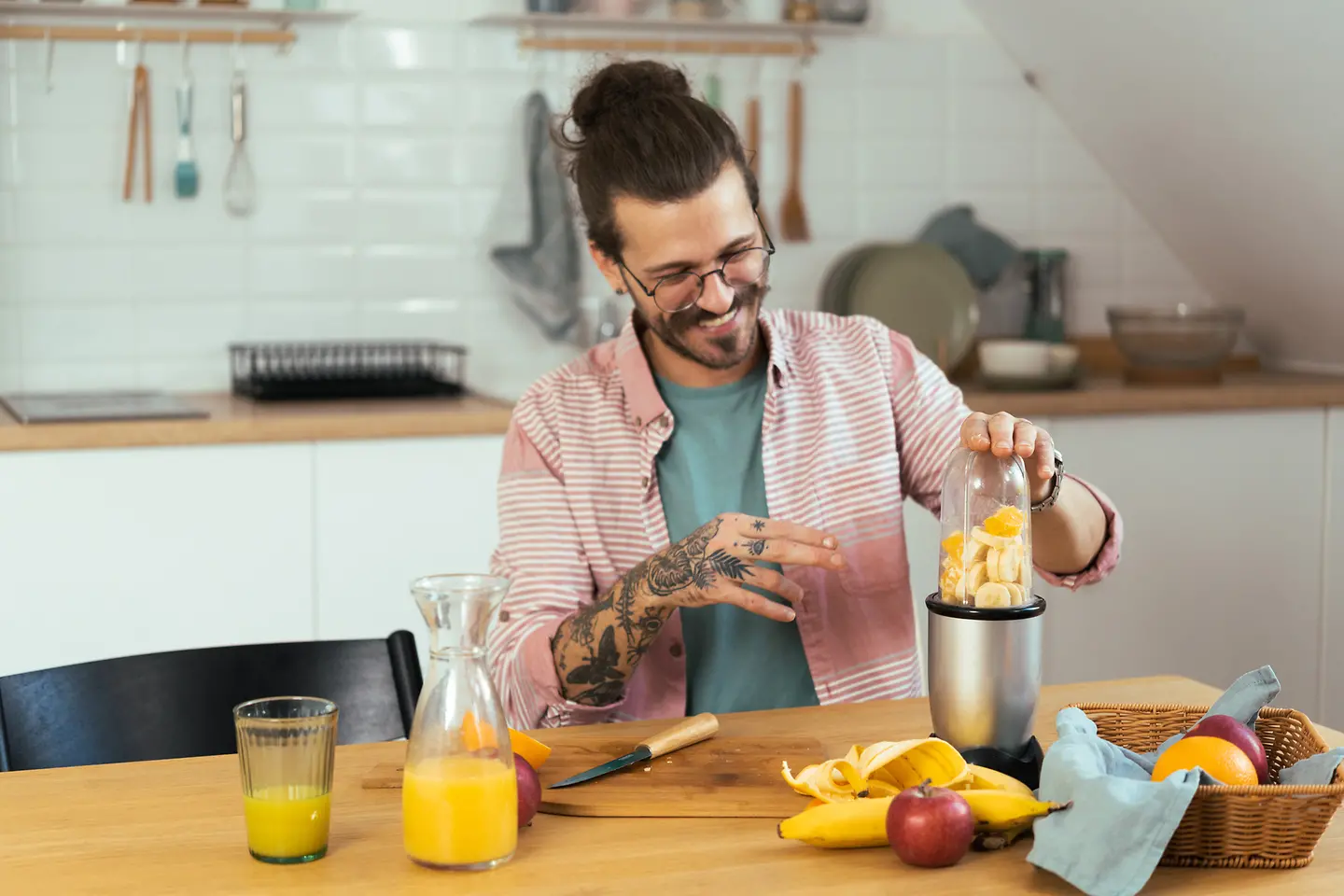 Ein Mann steht in der Küche und bereitet sich einen Saft-Smoothie zu.