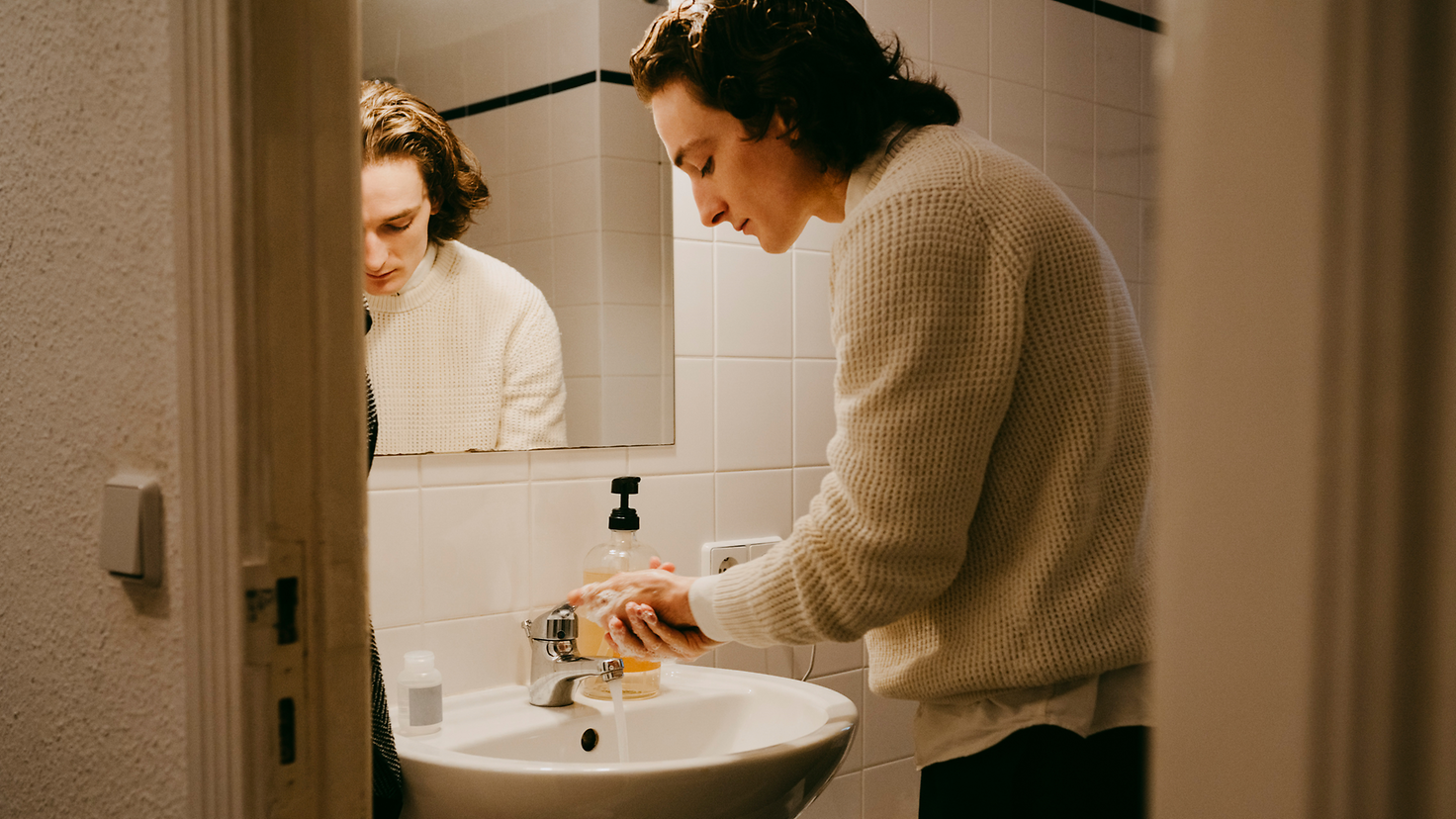 Ein junger Mann wäscht sich im Bad die Hände