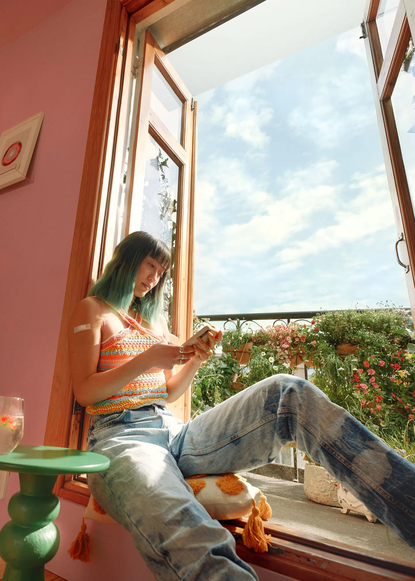 Eine Frau sitzt am Fenster und hält ein Smartphone in der Hand, auf dem sie die Barmer-App nutzt.
