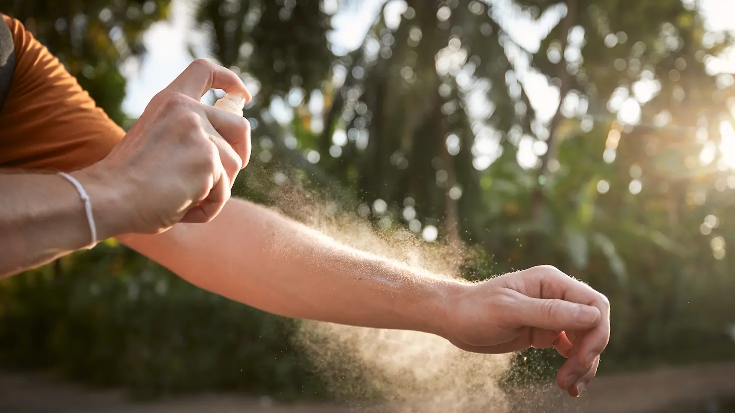 Ein Mann besprüht seinen Arm mit einem Mückenschutzmittel