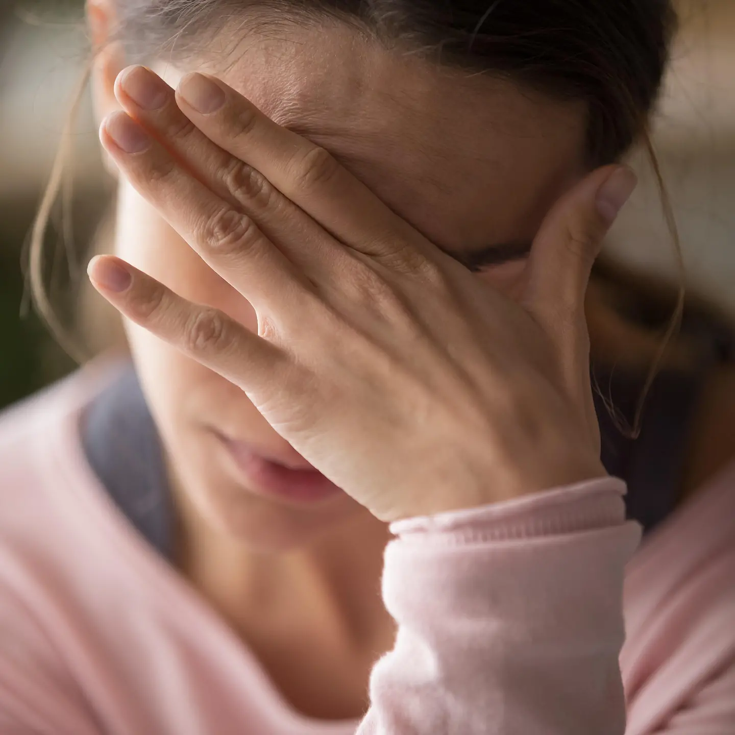Das Bild zeigt eine Frau, die eine Hand vor das Gesicht hält. 