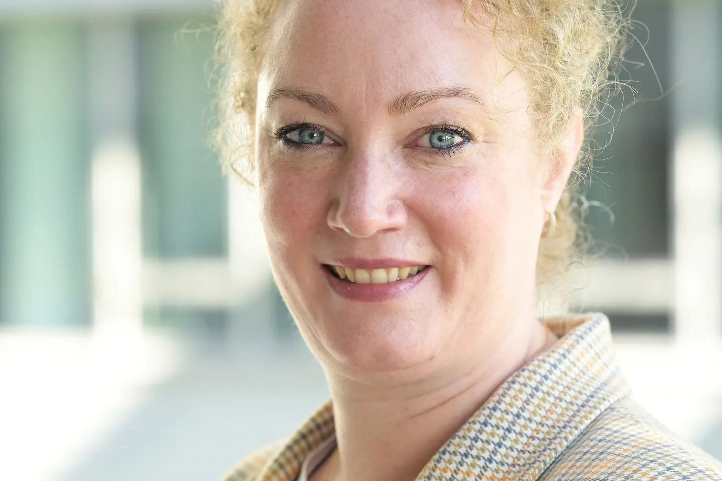 Eine Frau mit hochgesteckten, lockigen Haaren lächelt in die Kamera