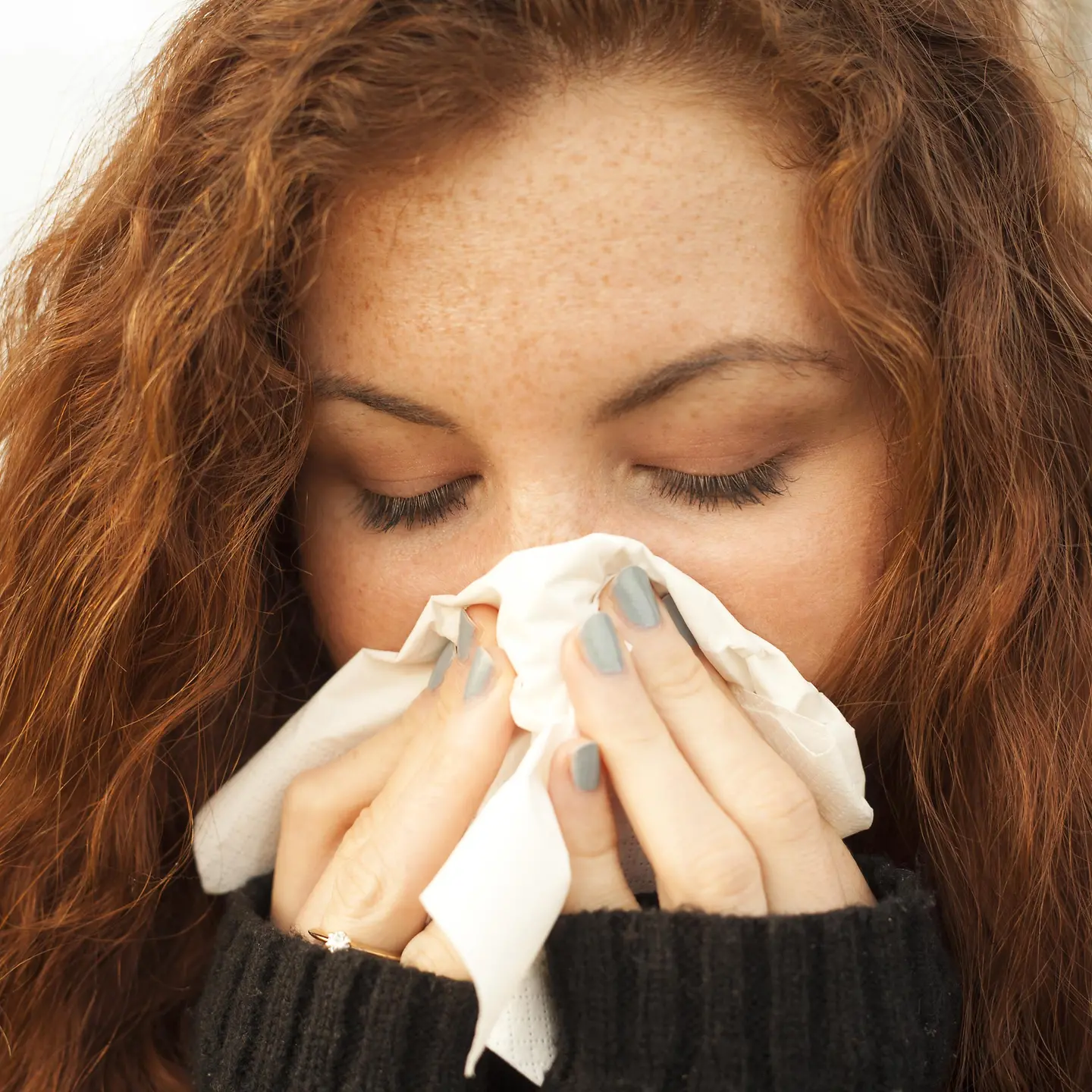 Frau schnieft ins Taschentuch wegen einer Allergie