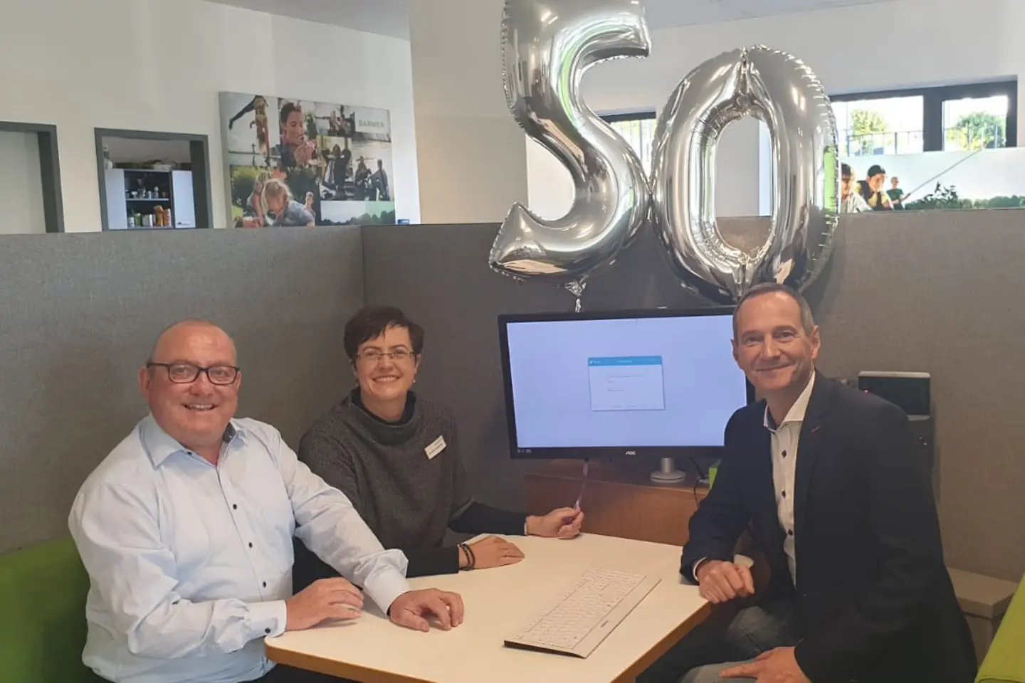 Drei Barmer-Beschäftigte sitzen an einem Beratungstisch in der Geschäftsstelle.