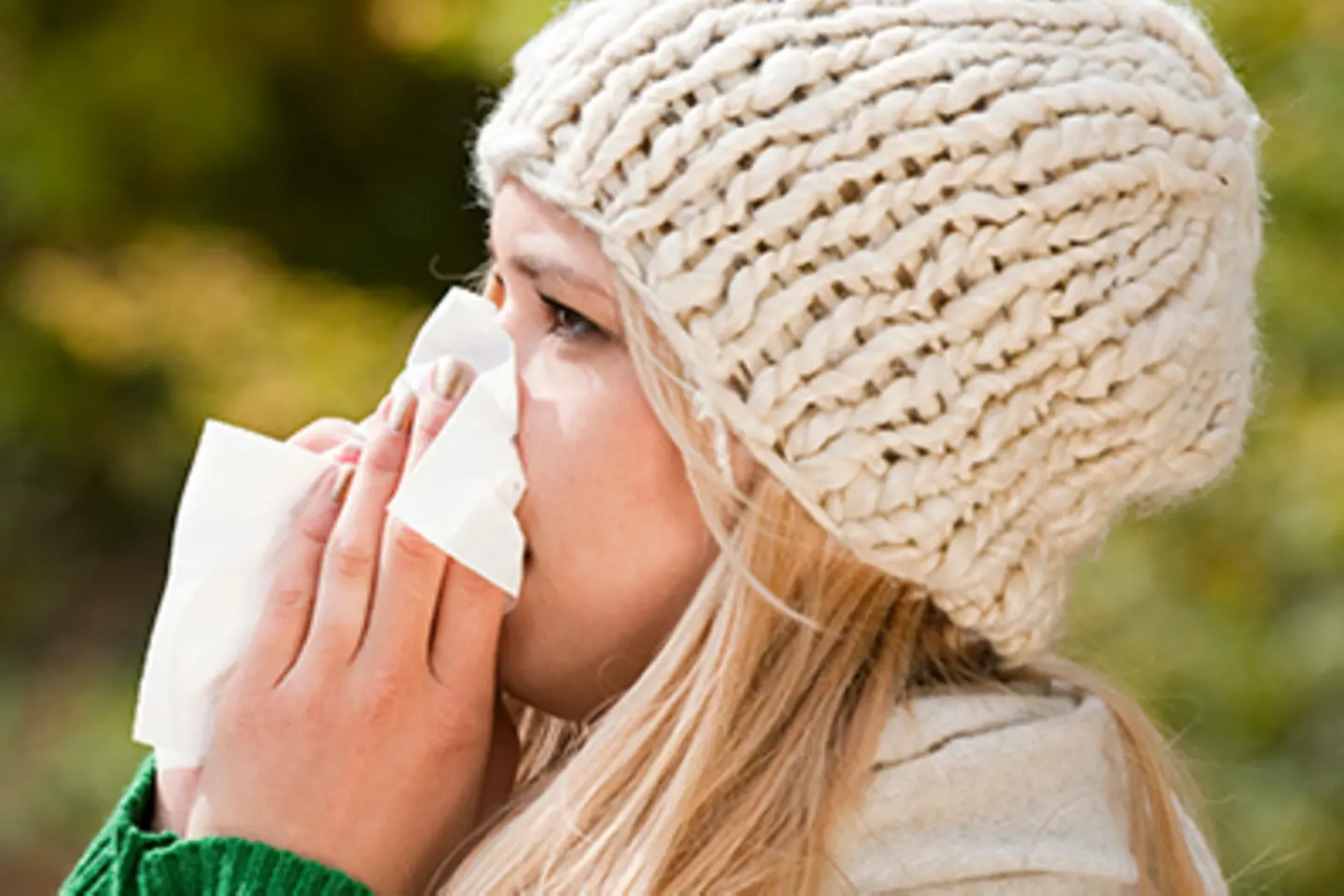 Zu sehen ist eine Fau, die sich die Nase putzt