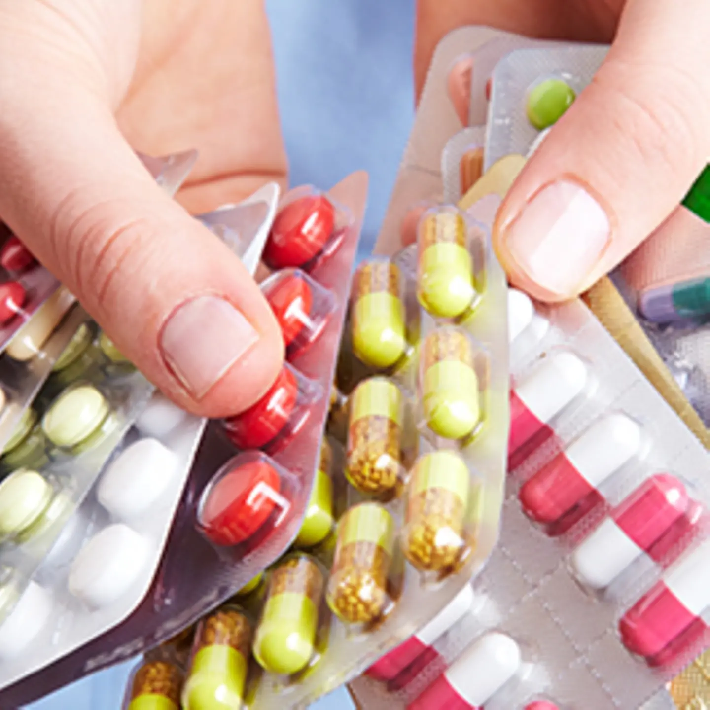 Zu sehen sind Hände, die gefächert mehrere Blisterpackungen Medikamente halten 