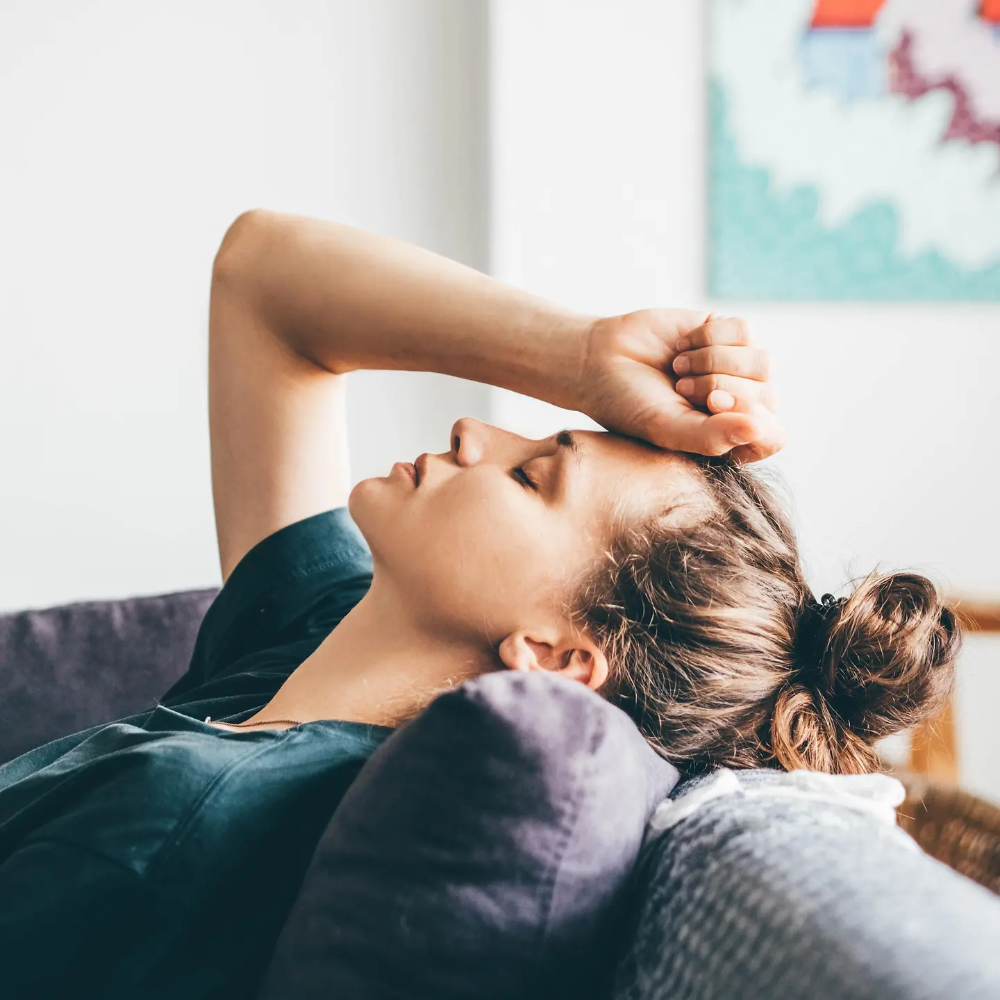 Zu sehen ist eine Frau, die sich eine Hand an den Kopf hält