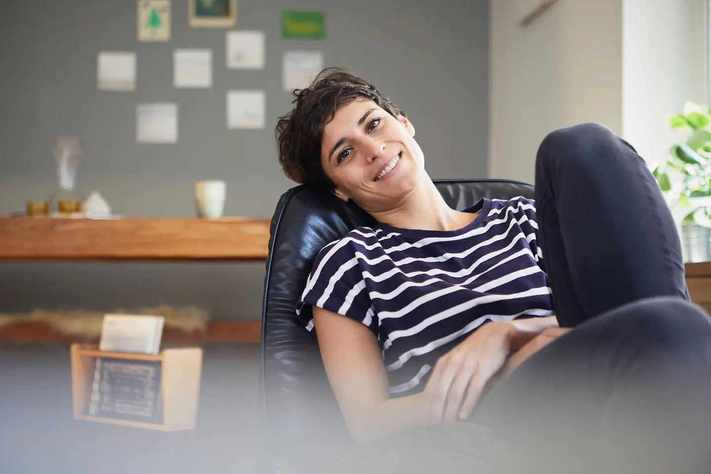 Eine junge Frau sitzt auf einem schwarzen Sessel und lächelt