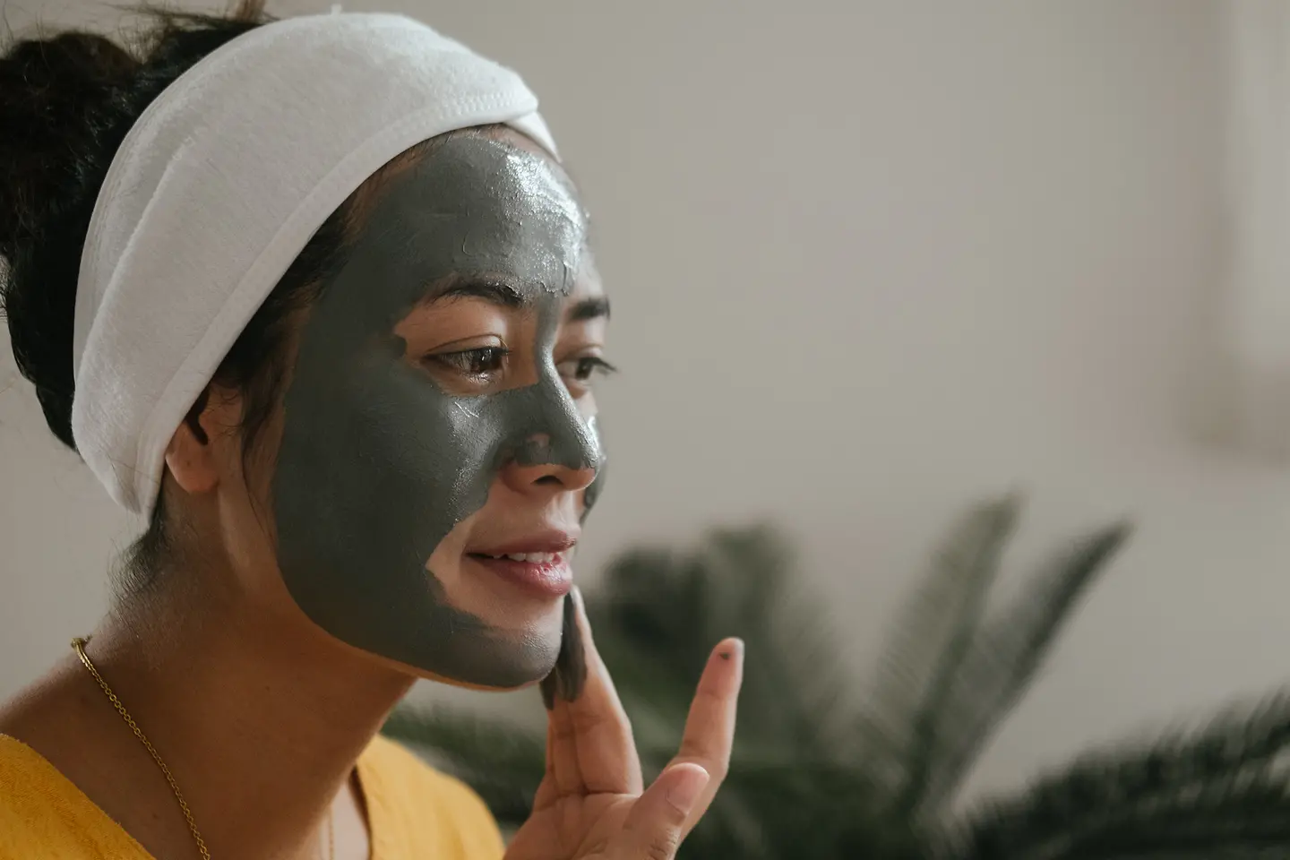 Eine junge Frau trägt eine Detox-Makse aus Tonerde auf