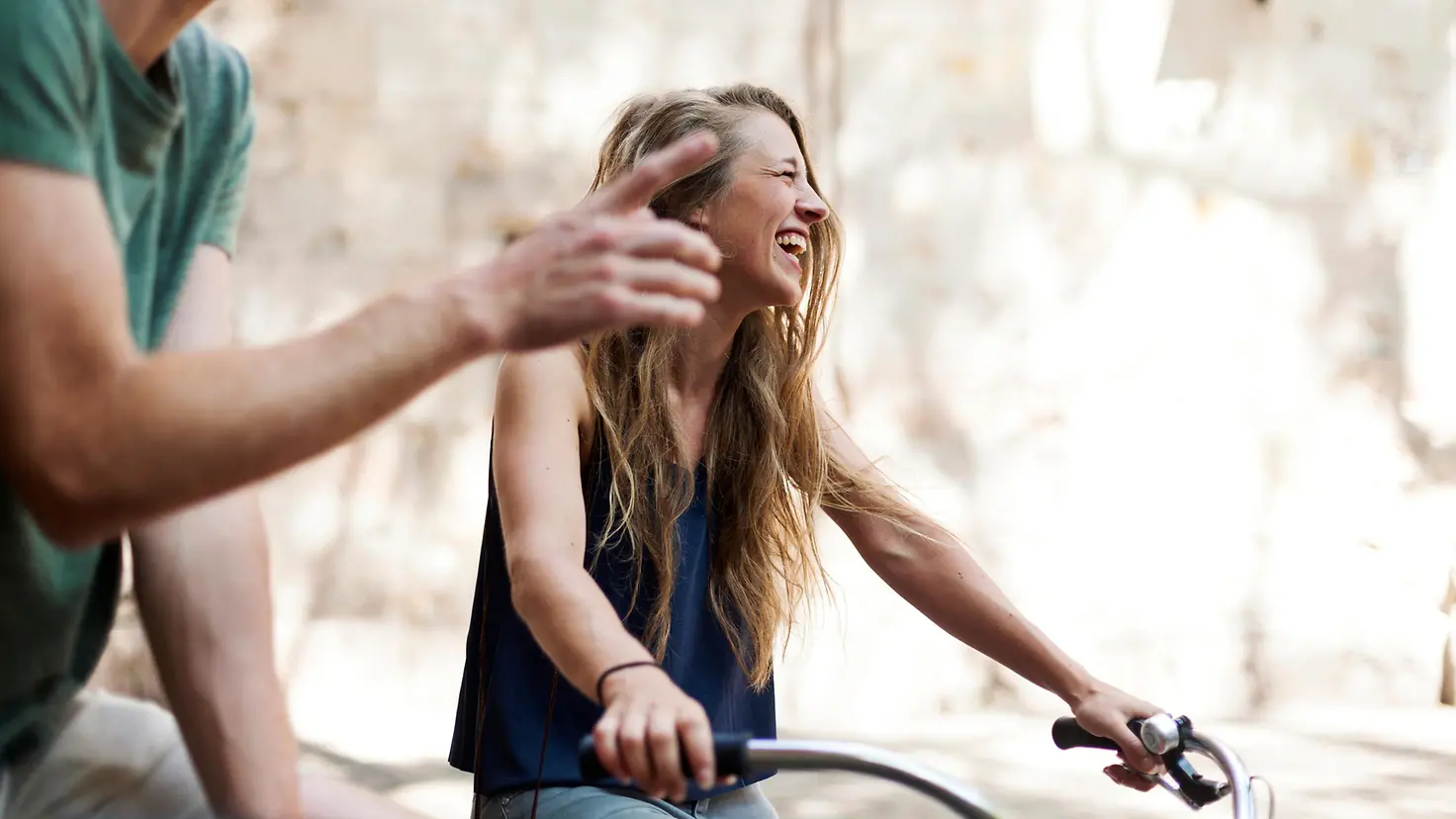 Junge Frau lachend auf einem Fahrrad.