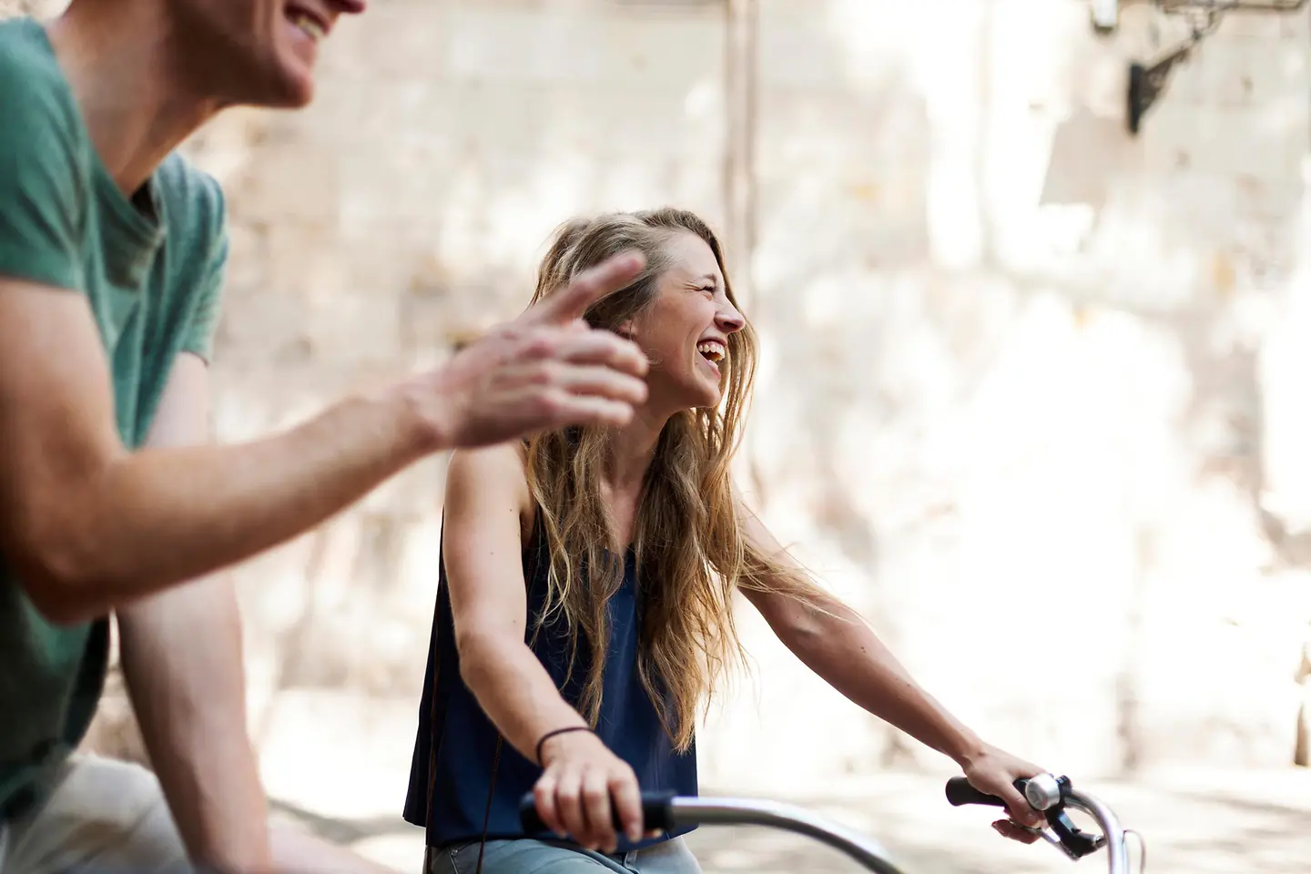 Junge Frau lachend auf einem Fahrrad.