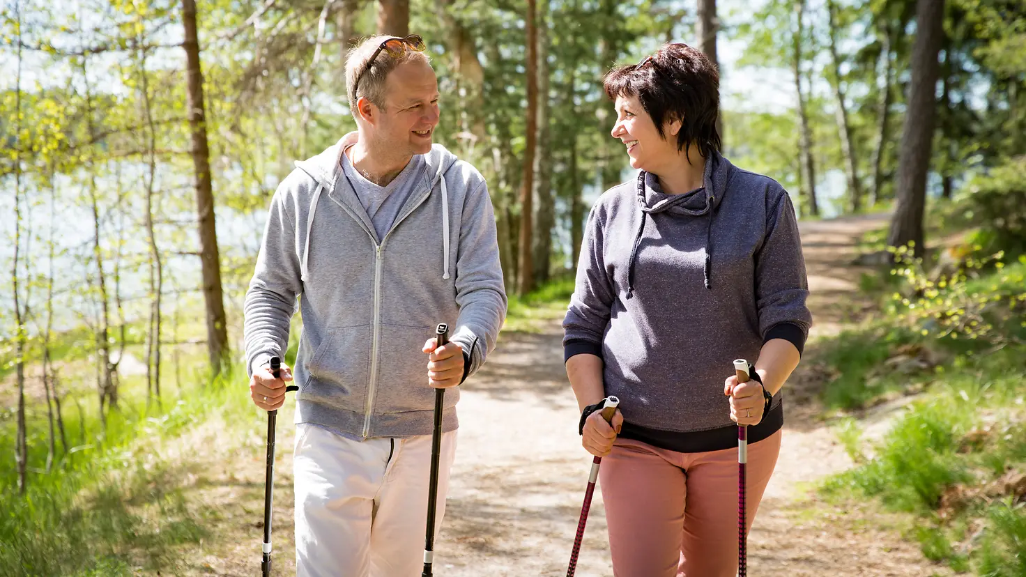 Zu sehen sind ein Mann und eine Frau beim Nordic Walking im Wald