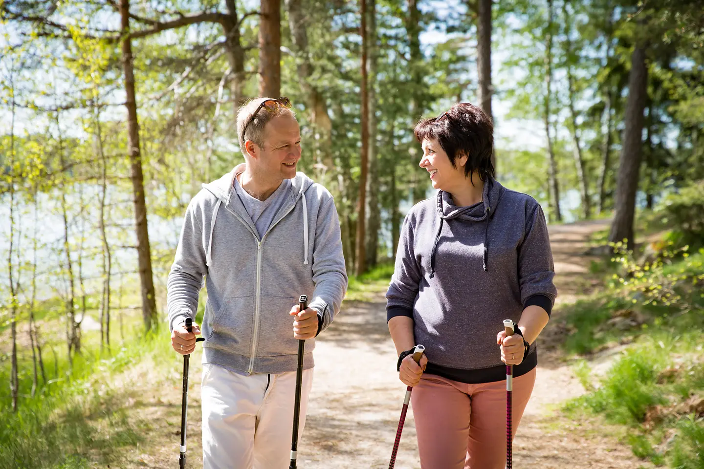 Zu sehen sind ein Mann und eine Frau beim Nordic Walking im Wald