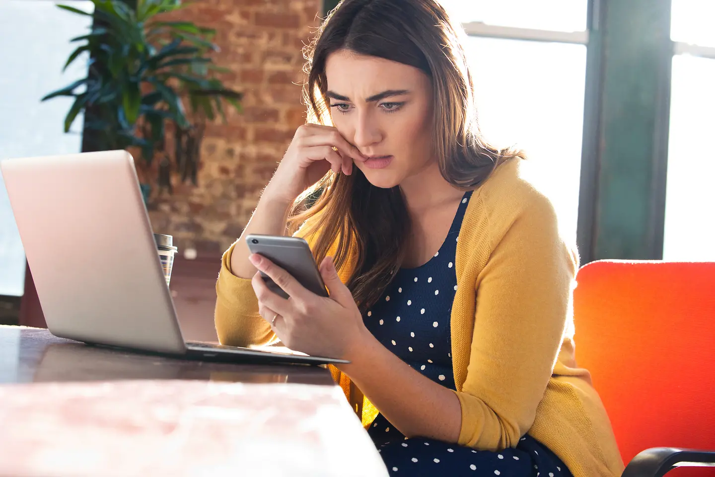 Junge Frau nutzt gleichzeitig Laptop und Mobiltelefon