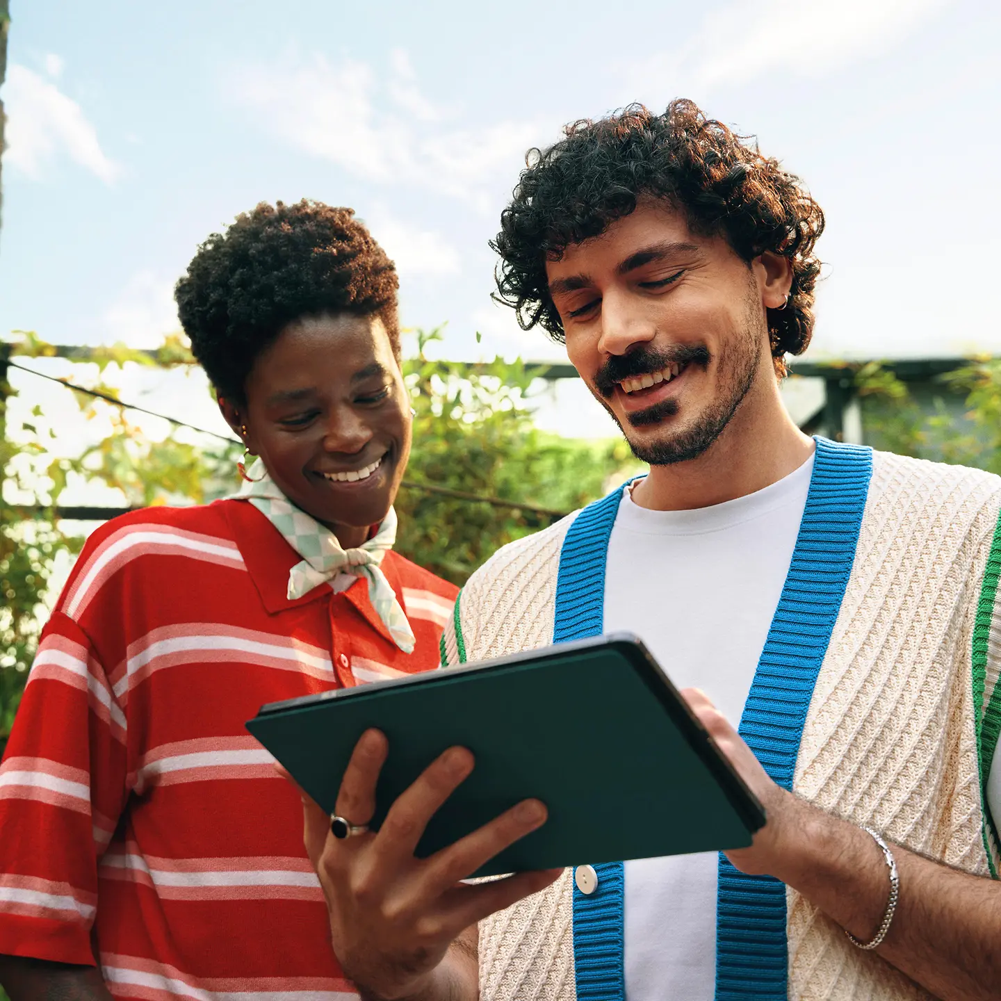 Ein junges Paar steht gemeinsam auf dem Balkon und informiert sich über die Geld-zurück-Tarife der Barmer per Tablet.