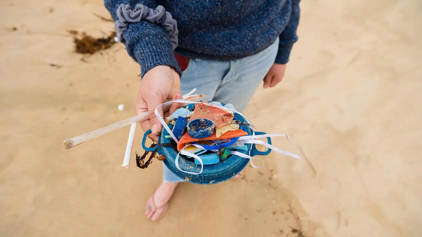 Eine Frau zeigt Plastikstücke, die sie am Strand gesammelt hat
