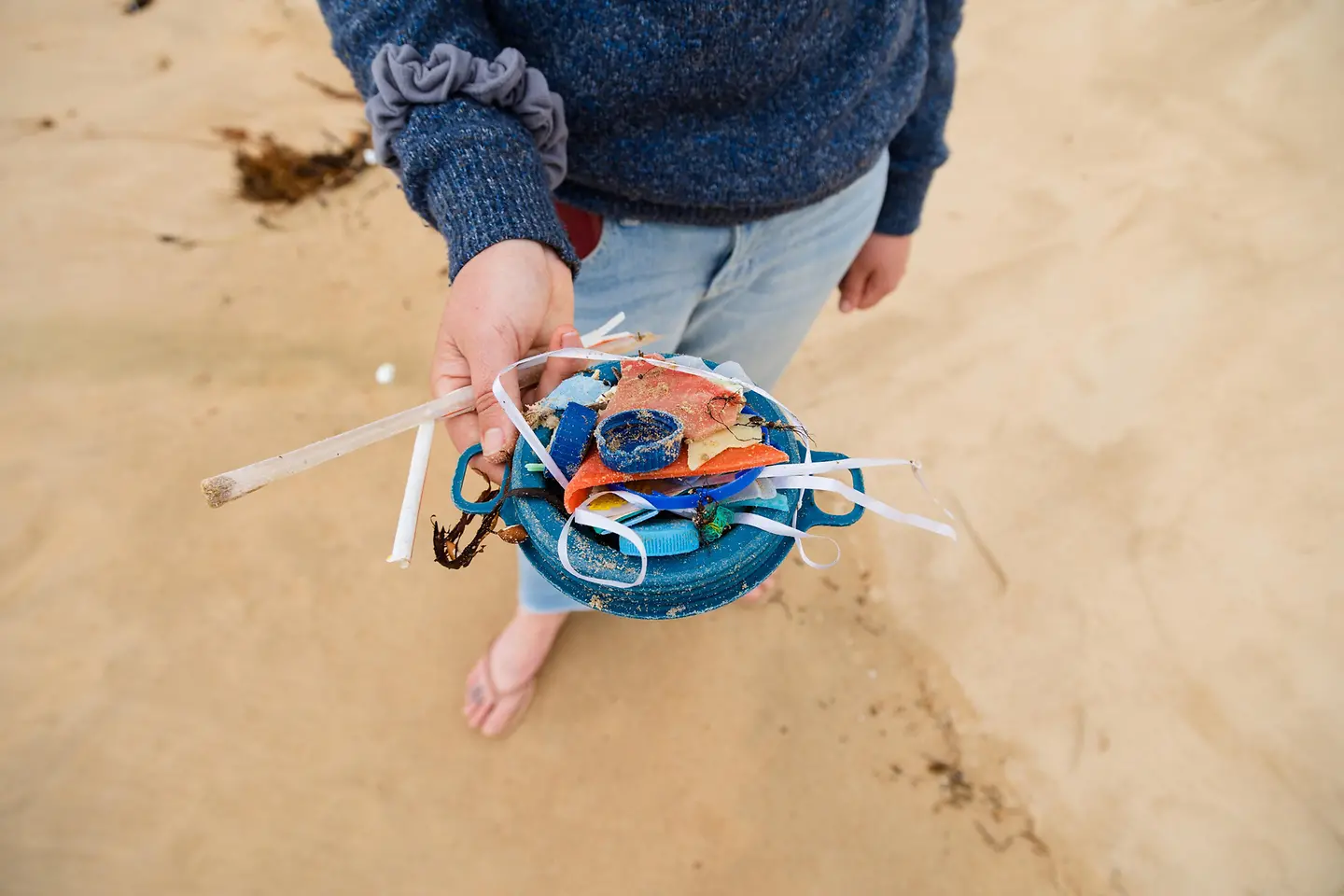 Eine Frau zeigt Plastikstücke, die sie am Strand gesammelt hat