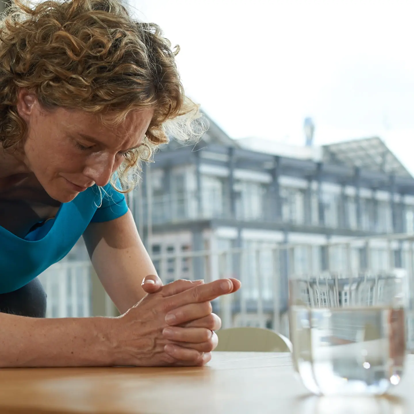 Eine Frau sitzt vor einem Glas Wasser