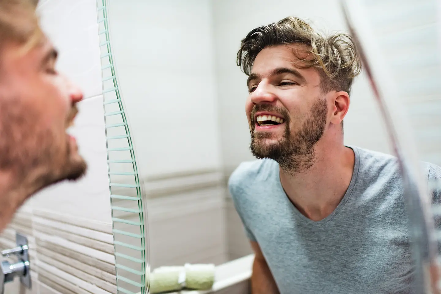 Ein Mann prüft seine Zähne im Spiegel auf Karies.